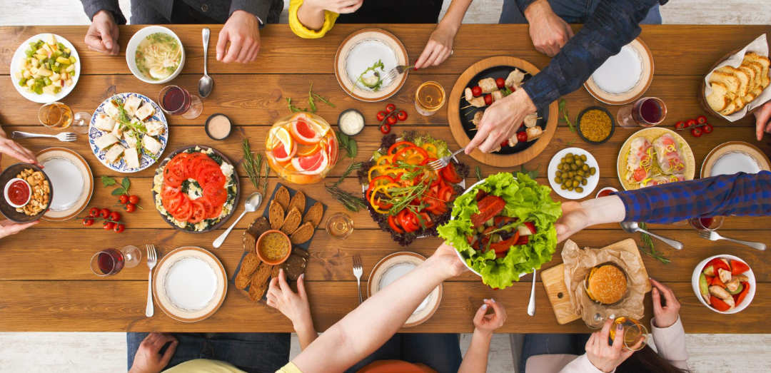 Birdview auf Tisch mit Essen und Personen, die zusammen feiern